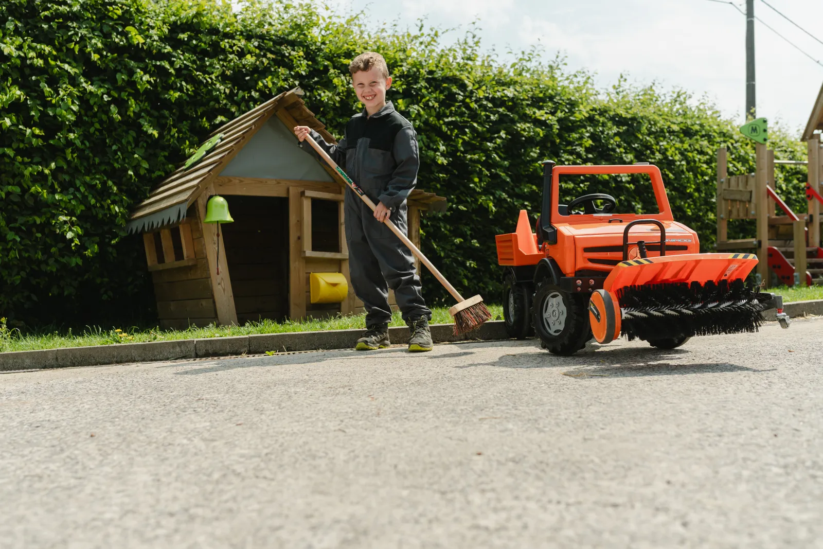 Kind speelt met een traptractor en aanbouwwerktuig bij FarmToys